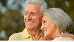 Smiling senior couple wearing beige leaning on each other in the park