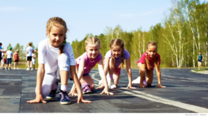 Four little girls in starter’s position on outdoor running track