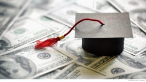 Graduation cap with red tassel on top of money pile