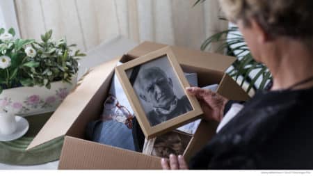 Woman packing a box of deceased husband's possessions; final expense insurance