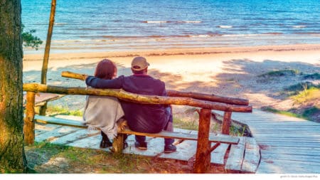 mature couple sitting on bench looking at lake