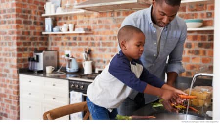 Father and son rinsing vegetables as they prepare a healthy meal